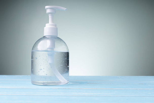 The bottle alcohol gel isolated on blue table with copy space, and green background. Prevention from coronavirus everyone cleaning hands every time. - Foto, imagen