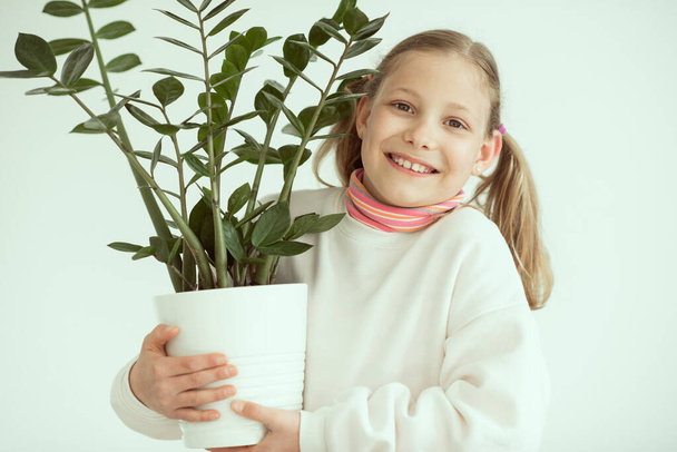 Happy adorable child girl holding green plant with love and care to flowers and nature - Fotoğraf, Görsel