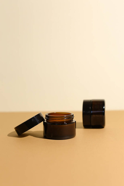 A few beauty hygiene Amber glass jars on neutral background - Zdjęcie, obraz