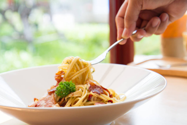 Spaghetti würzig mit Speck, Petersilie und Parmesan Frischer Pfeffer, Basilikumblatt. Pasta Carbonara auf weißem Teller. Italienisches Ernährungskonzept. - Foto, Bild