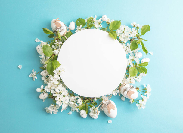 Easter  floral, eggs, composition with paper round blank in the centre of blue background. Branding mock up, holiday marketing concept. Composition of cherry and white flowers is lined with frame around. Greeting card template. Happy womans day, spri - Φωτογραφία, εικόνα