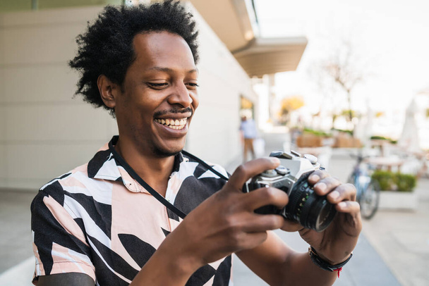 Afro tourist man taking photographs with camera outdoors. - Valokuva, kuva
