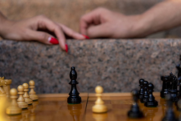 Chess board with figures on a sunny day in the park with bokeh and blurred background by a pair of female and male hands - Photo, Image