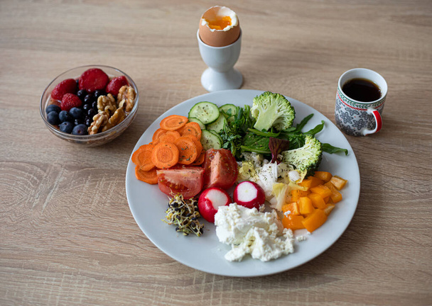 A healthy and tasty breakfast. Soft boiled egg, cottage cheese, colorful vegetables, berries, nuts and coffee - Photo, Image