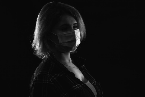 Junge schöne Frau in medizinischer Maske vor dunklem Hintergrund - Foto, Bild