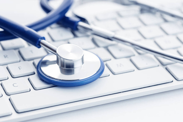 Zavřít stetoskop na klávesnici počítače na bílém stole. Online zdravotní péče nebo telemedicína koncept. Lékařské zázemí - Fotografie, Obrázek