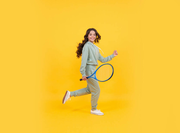 happy energetic kid jump in sportswear with tennis racket running to success on yellow background, active childhood. - Foto, Imagen