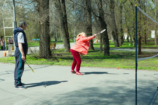 Dnepropetrovsk, Ukraine - 04.22.2021: A group of elderly people doing health-improving gymnastics in the park. Old men play minitenis. - Foto, imagen