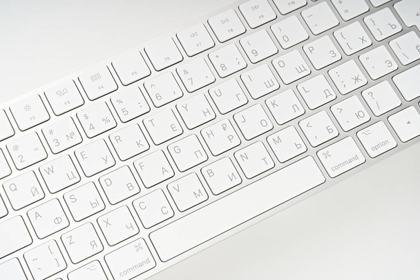 Белая беспроводная клавиатура компьютера изолирована на белом фоне. Раскладка клавиатуры на русском и английском языках - Фото, изображение