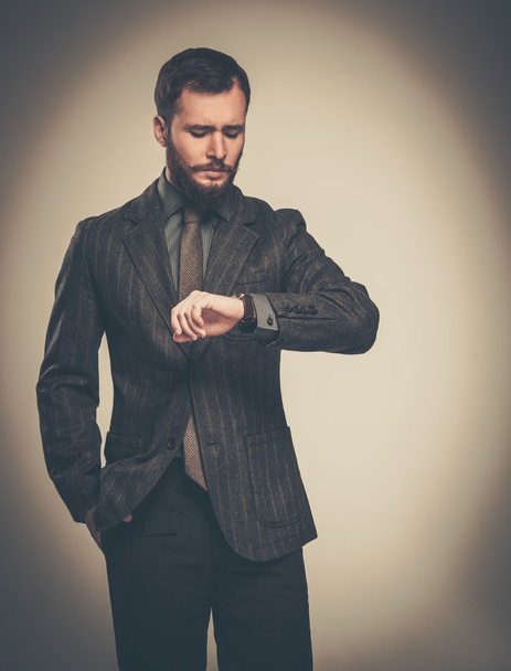 hezký-oblečený muž s plnovousem, při pohledu na své hodinky - Fotografie, Obrázek