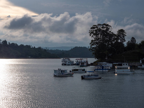 Guatape, Antioquia, Colombia - 3 de abril de 2021: Vista panorámica de varias pequeñas embarcaciones de ocio en el lago en Guatape Marina al anochecer - Foto, imagen