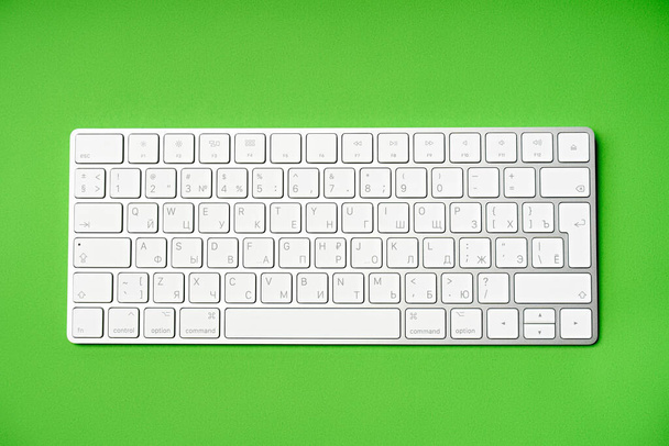 Bílá bezdrátová počítačová klávesnice izolovaná na zeleném pozadí. Rozvržení ruské / anglické klávesnice - Fotografie, Obrázek