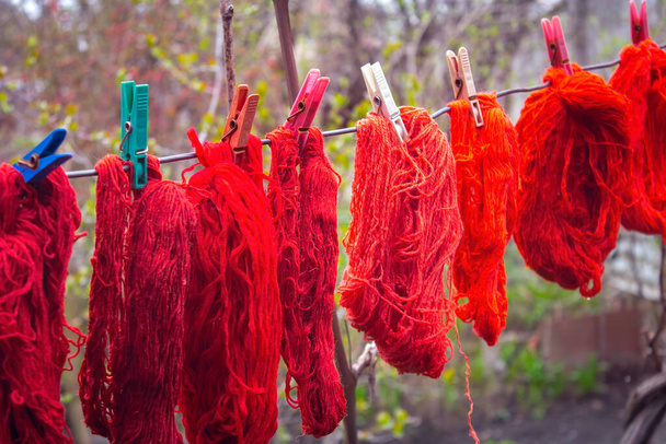 Bunte Wollfäden hängen an einer Wäscheleine mit Wäscheklammern im Freien - Foto, Bild