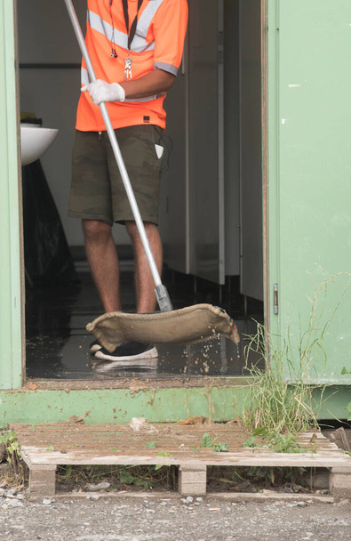 ένα άτομο με εξοπλισμό καθαρισμού βρίσκεται σε υγρό καθαρισμό δαπέδων - Φωτογραφία, εικόνα