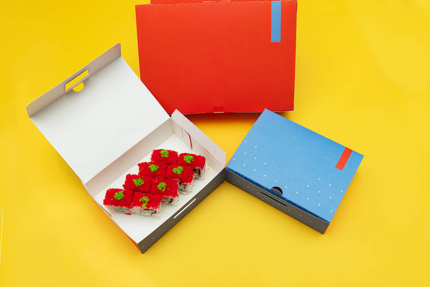 otwarte pudełka z bułkami sushi i butelką świeżego soku, opakowania żywności wykonane z ekologicznych materiałów, piękne jednorazowe zastawy stołowe w jasnych kolorach - Zdjęcie, obraz