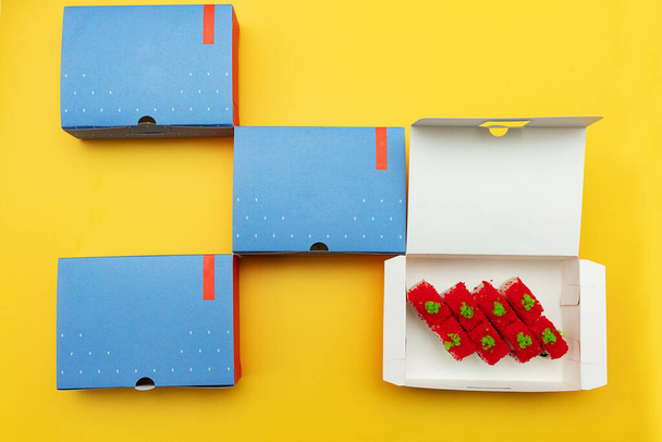 caixas abertas com rolos de sushi e uma garrafa de suco fresco, embalagens de entrega de alimentos feitos de materiais ecológicos, belos utensílios de mesa descartáveis em cores brilhantes - Foto, Imagem
