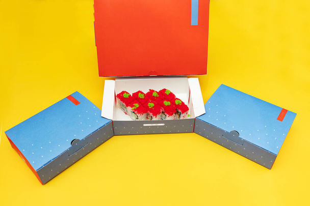 cajas abiertas con rollos de sushi y una botella de jugo fresco, envases de entrega de alimentos hechos de materiales ecológicos, vajilla desechable hermosa en colores brillantes - Foto, imagen