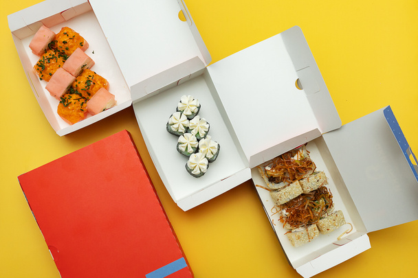 scatole aperte con involtini di sushi e una bottiglia di succo fresco, imballaggi per la consegna di alimenti realizzati con materiali ecologici, bellissime stoviglie usa e getta in colori vivaci - Foto, immagini