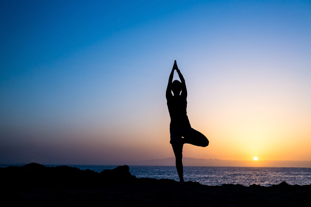 Mujer haciendo yoga árbol puesta del sol silueta
 - Foto, imagen
