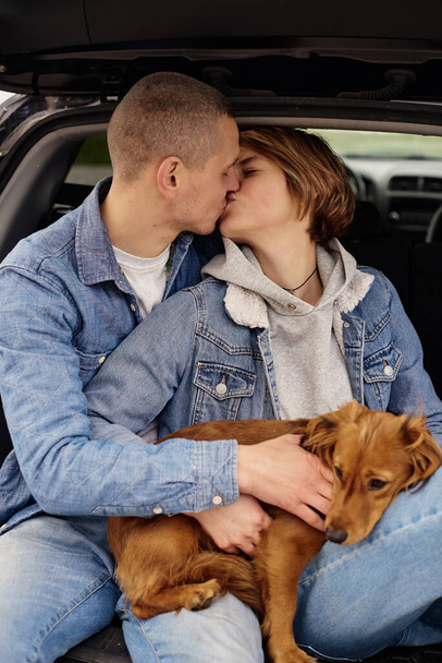 Young couple resting in the car with their dog. - Fotografie, Obrázek