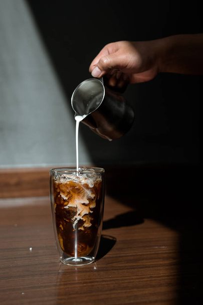 Barista pouring milk into a glass of iced coffee - Foto, Imagem