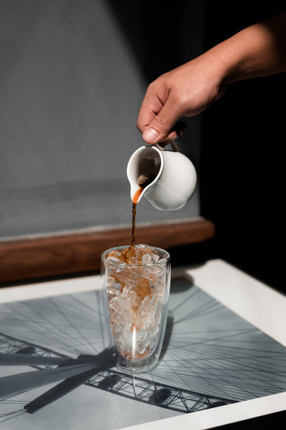 Бариста виливає молоко у склянку замороженої кави. - Фото, зображення