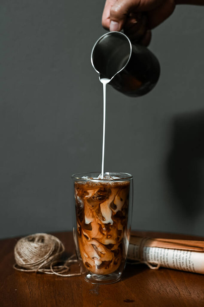 アイスコーヒーのグラスにミルクを注ぐバリスタ - 写真・画像