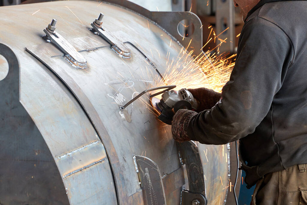 İşçiler boyanmamış metal ürünleri elle açılı öğütücüyle işlerler. - Fotoğraf, Görsel