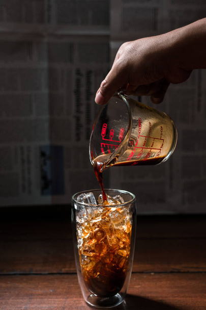 Barista giet melk in een glas ijskoffie - Foto, afbeelding