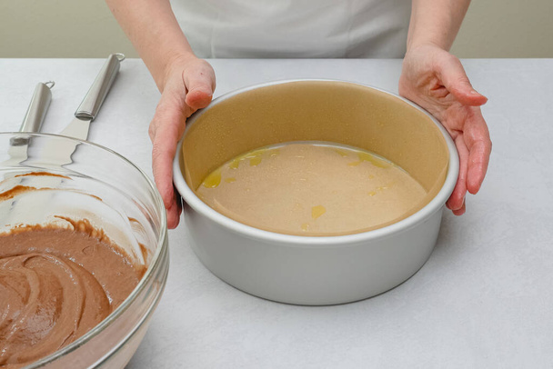 Mit Pergamentpapier ausgekleidete Kuchenform in Großaufnahme auf dem Küchentisch. Schokoladenkuchen Schritt für Schritt Rezept, Nahaufnahme Backvorgang - Foto, Bild