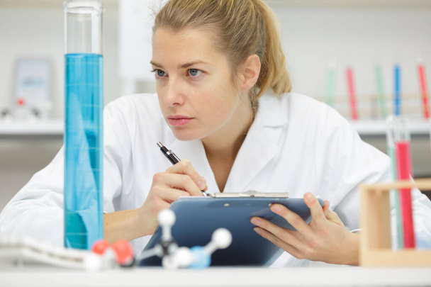positive minded woman looking at a test tube - Photo, image