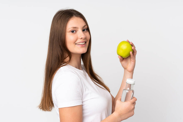 Ragazza caucasica adolescente isolata su sfondo bianco con una mela e con una bottiglia d'acqua - Foto, immagini