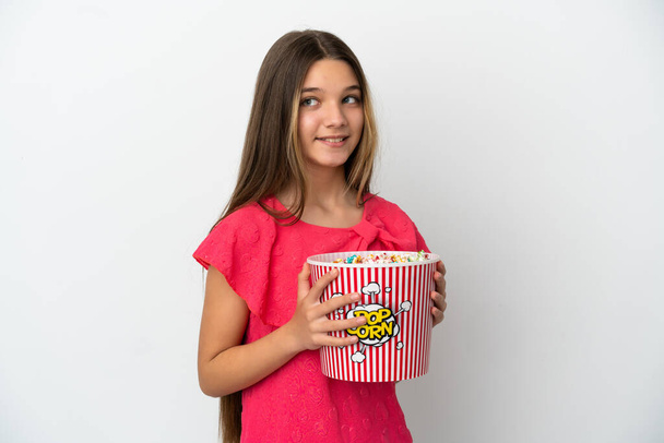 Petite fille sur fond blanc isolé tenant un grand seau de popcorns - Photo, image