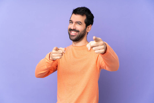 Белый красивый мужчина на изолированном фиолетовом фоне указывает пальцем на тебя, улыбаясь - Фото, изображение