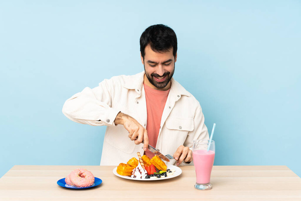 Άνθρωπος στο τραπέζι που τρώει βάφλες και μιλκσέικ. - Φωτογραφία, εικόνα