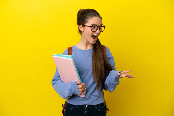 Студентка на изолированном желтом фоне с удивленным выражением лица, глядя в сторону - Фото, изображение