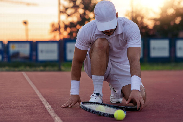 スポーツだ。テニスコートで男とテニスラケットとボールを間近に見る. - 写真・画像