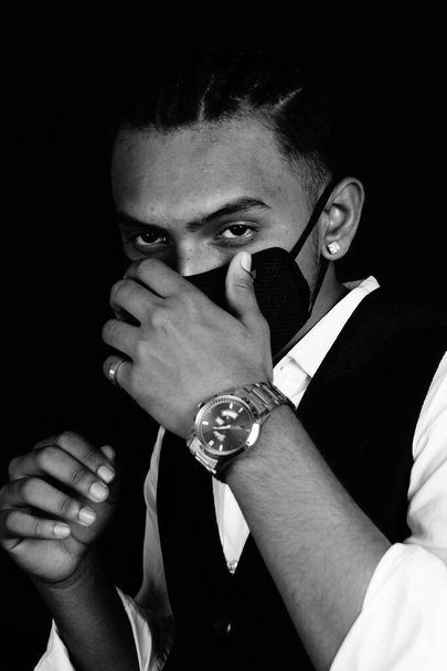 A black and white portrait of a handsome Indian man in a suit wearing a facemask and silver watch - Fotografie, Obrázek