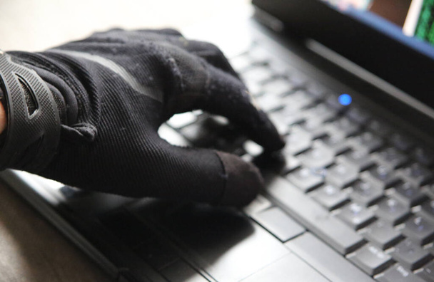 A closeup of a person in gloves using the computer - concept of cybersecurity and threat of getting hacked - Foto, Imagen