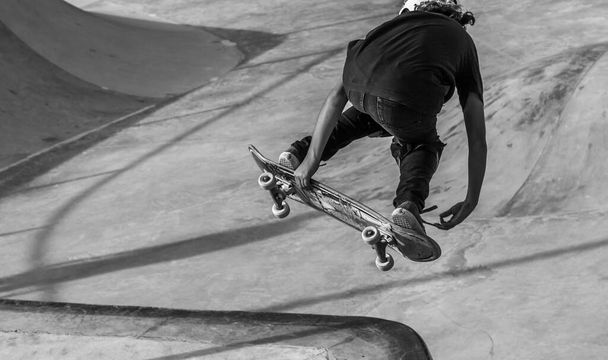A grayscale shot of a person skating in a skatepark - Valokuva, kuva