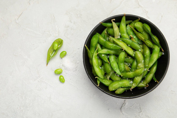 Raw edamame soya beans with salt and sauce on light gray background. Top view, copy space - Фото, зображення
