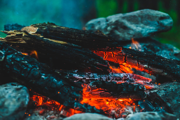 Яркий тлеющий лес сгорел в огне крупным планом. Атмосферный теплый фон с оранжевым пламенем костра и голубым дымом. Чудесное изображение костра в полной раме. Горящие дрова в прекрасном огне. - Фото, изображение