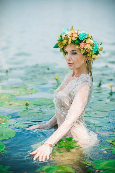 長い白いレースのドレスと花輪で素晴らしい、湖ニンフ。芸術写真、神秘的なシーン。ヨーロッパの魔女。おとぎ話 - 写真・画像