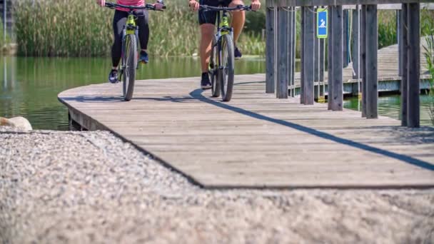 couple cycling, wheels and tires approach from wooden pathway, low angle. - Footage, Video