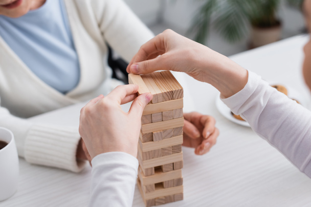 partial view of nurse playing wood blocks game with aged woman on blurred background - Photo, Image