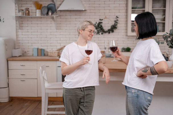 boldog leszbikus pár kezében pohár vörösbor a konyhában  - Fotó, kép