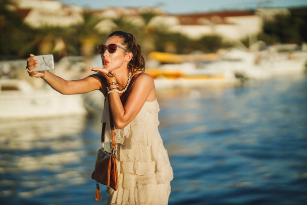 Laukaus nuori nainen ottaa selfie hänen älypuhelin samalla tutkia ihana meren rannalla Välimeren. - Valokuva, kuva
