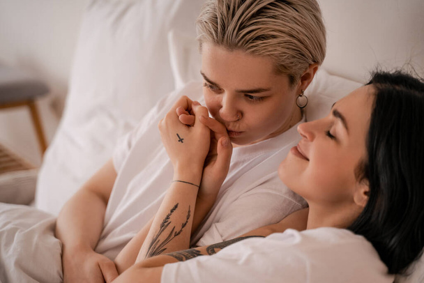 junges lesbisches Paar liegt im Bett und hält die Hände - Foto, Bild