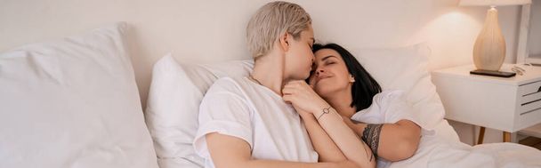 young lesbian couple lying in bed and holding hands, banner - Photo, Image