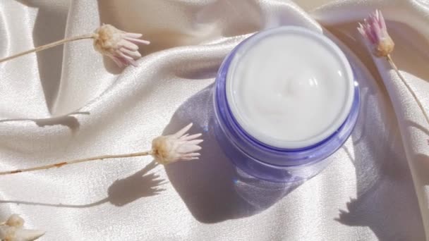 Blauw glas crème pot mockup op gladde zijde stof in zonlicht met bloemen schaduw Natuurlijke huidverzorging moisturizer cosmetische, gezonde gloeiende huid SPA wellness gezicht lichaam hydratatie behandeling UV-bescherming - Video
